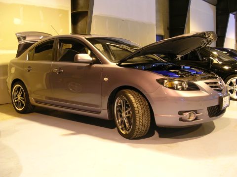 1996 Ford Probe - A gray Mazda 3 sedan is parked indoors with its hood open, revealing a blue engine cover.
