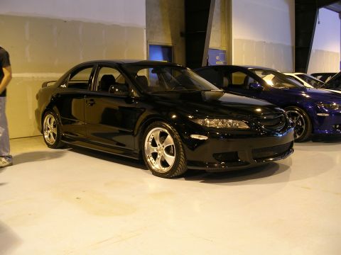1996 Ford Probe - A black sedan with aftermarket wheels is displayed indoors, with other vehicles visible in the background.