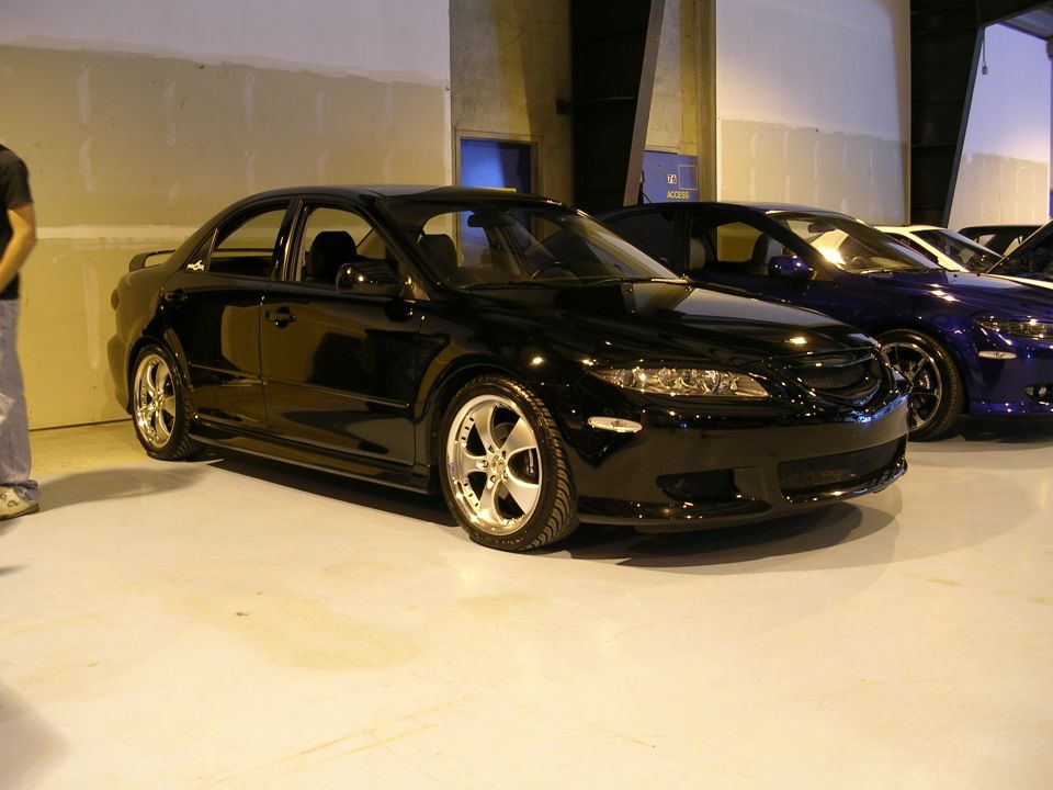 Black sedan with custom wheels, parked indoors