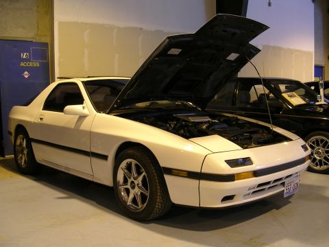 1996 Ford Probe - A white Mazda RX-7 is parked indoors with its hood open, revealing the engine compartment.