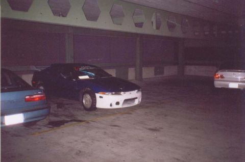 1993 Ford Taurus - Two cars are parked in a dimly lit parking garage.
