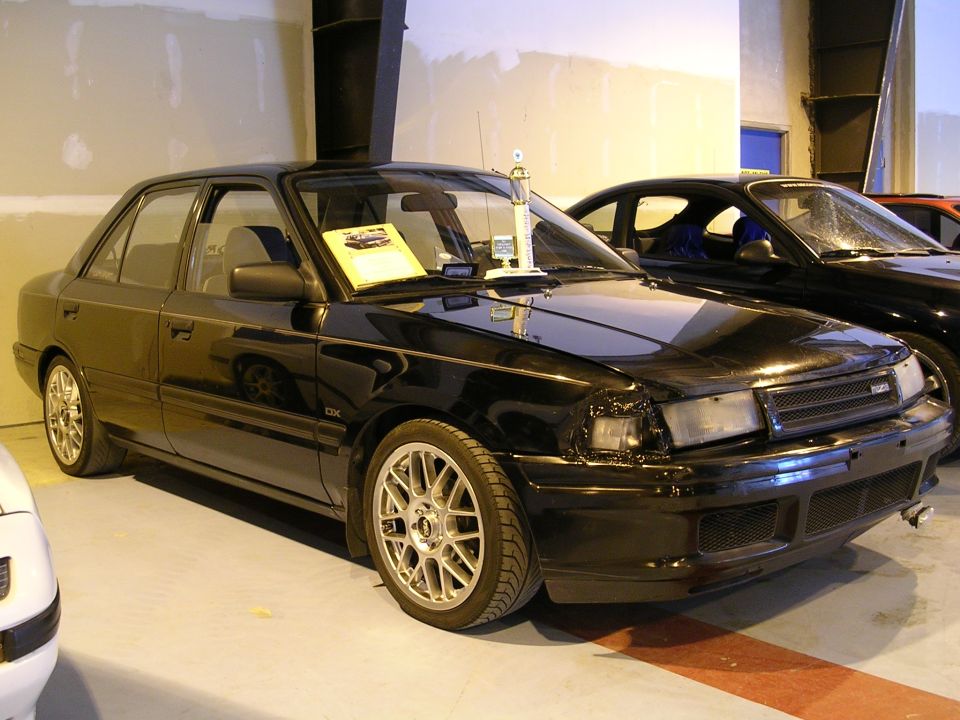 Black sedan with aftermarket wheels and a trophy on the dashboard