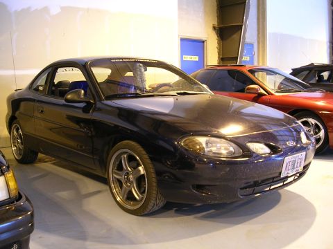 1996 Ford Probe - A 1996 Ford Probe coupe is parked indoors next to another vehicle.