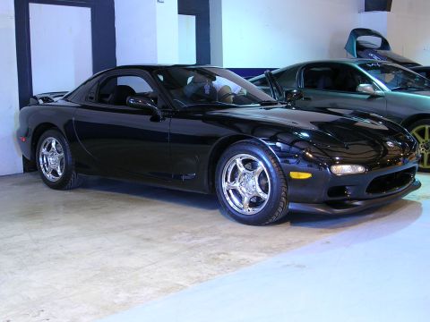 1996 Ford Probe - A black Mazda RX-7 is parked indoors, with another vehicle visible behind it.