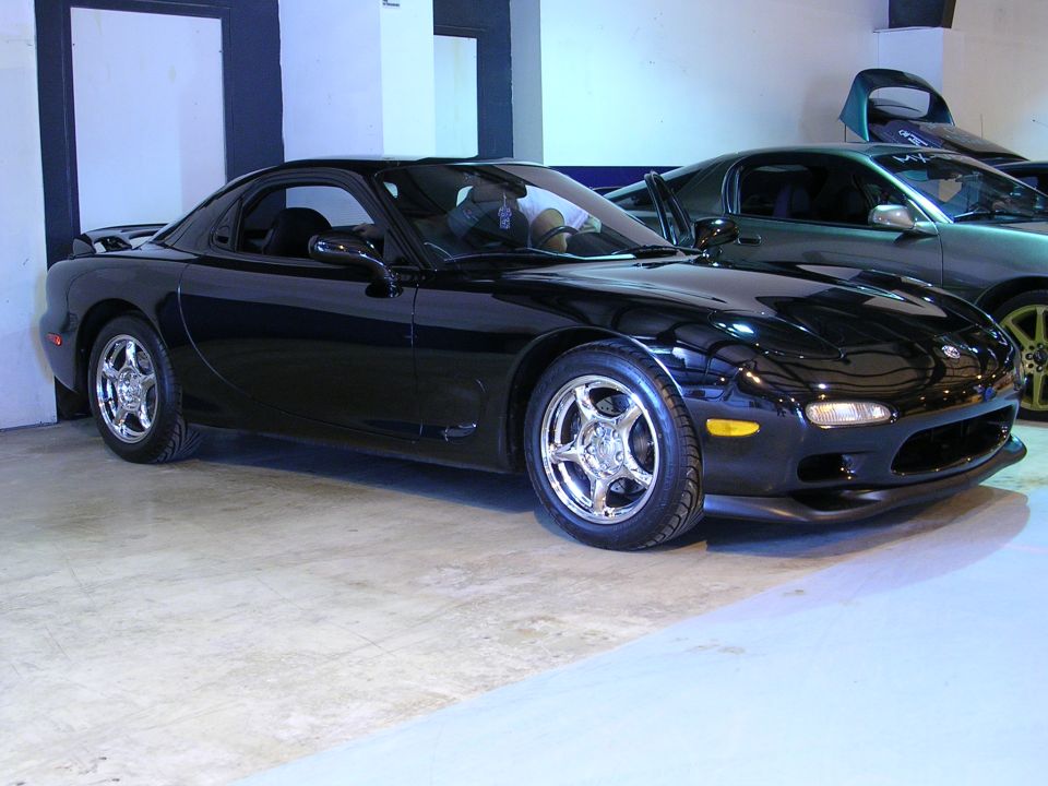 Black Mazda RX-7 parked indoors next to another car