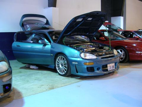 1996 Ford Probe - A teal 1996 Ford Probe is displayed with its hood and trunk open, parked next to other vehicles.