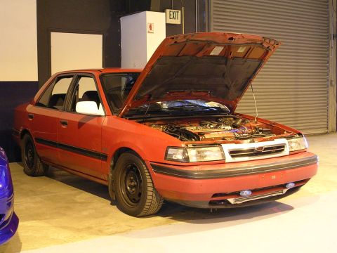 1996 Ford Probe - Red sedan with hood open, revealing the engine bay. The vehicle is viewed from the front 3/4 angle.