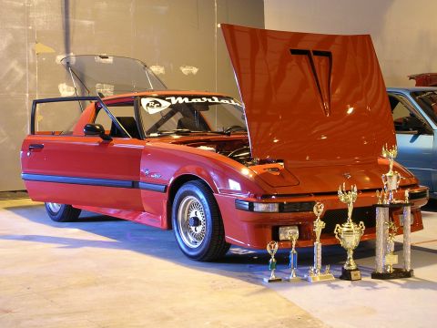 1996 Ford Probe - Red sports car on display with trophies, hood and trunk open; another vehicle is in the background.