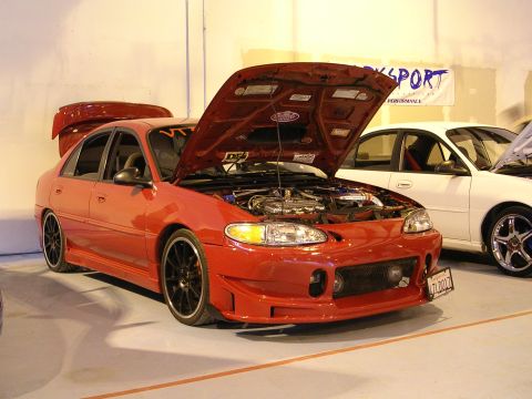 1996 Ford Probe - A red 1996 Ford Probe sedan is displayed with its hood open, revealing the engine bay.