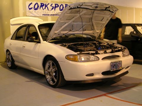 1996 Ford Probe - White 1996 Ford Probe with hood open, displaying its engine and aftermarket wheels.