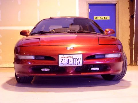 1996 Ford Probe - A red 1996 Ford Probe is parked indoors, facing forward, with a blue door and an exit sign in the background.