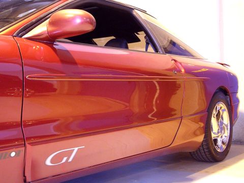 1996 Ford Probe - Side profile of a red car, a prominent 'GT' badge on the lower door panel.