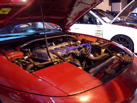 1996 Ford Probe - The engine bay of a red 1996 Ford Probe is visible, with the hood open, revealing the engine and other components.