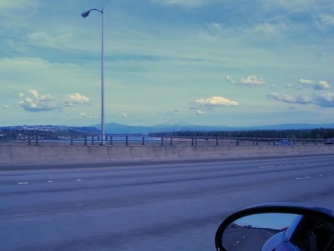 1996 Ford Probe - Driving across a bridge with a scenic view of mountains and water under a partly cloudy sky.