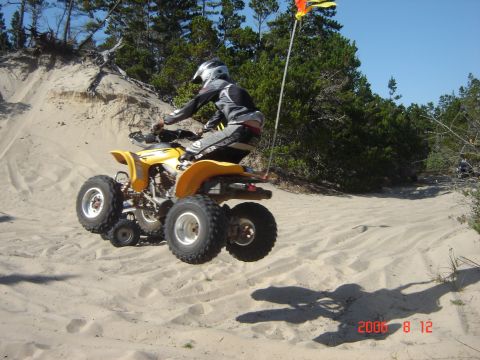 1993 Ford Bronco - ATV rider catches air while cresting a sand dune on a sunny day.