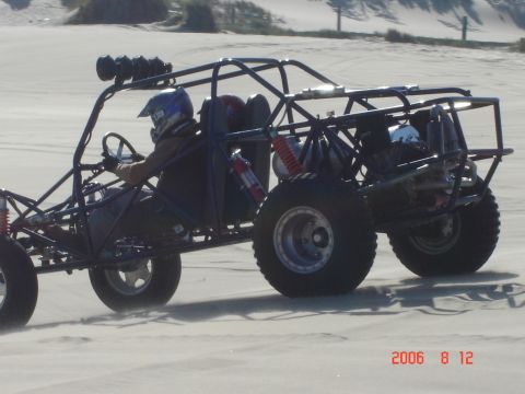 1993 Ford Bronco - A dune buggy navigates a sandy landscape, kicking up dust as it moves.