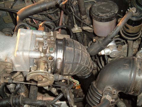 1991 Ford Probe - Close-up view of an engine bay, focusing on the throttle body, intake hose, and brake fluid reservoir. The registry claims it is a 1991 For…