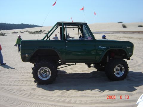 1993 Ford Bronco - Modified Ford Bronco with roll cage on sand dunes, likely from the 1978-1979 model years.