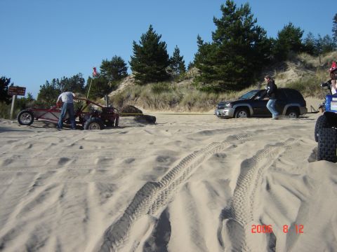 1993 Ford Bronco - Two vehicles, a dune buggy and an SUV, are stuck in the sand on a sunny day.