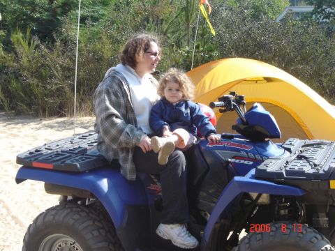 1993 Ford Bronco - A woman and child sit on a blue ATV with a yellow tent behind them on a sandy area.