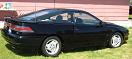 1991 Ford Probe - A black 1991 Ford Probe coupe is parked on grass with a building in the background.