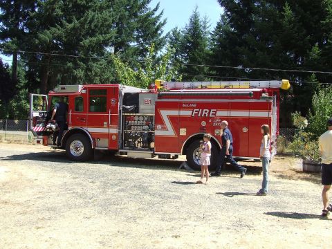 1976 Ford F-150 - A red fire truck is parked on a gravel surface with trees in the background.