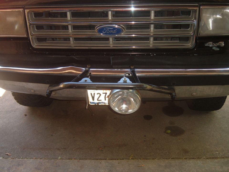 Dark Ford 4x4 truck front grille with blue Ford oval, chrome bumper and round fog light