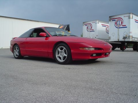 1996 Ford Probe - Red 1996 Ford Probe parked outdoors with trailers in the background.
