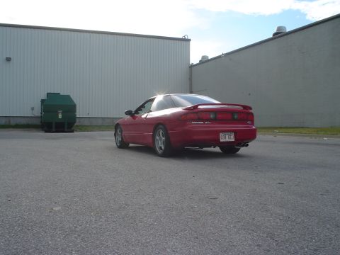 1996 Ford Probe - A red 1996 Ford Probe is parked in an asphalt lot next to a large green dumpster.