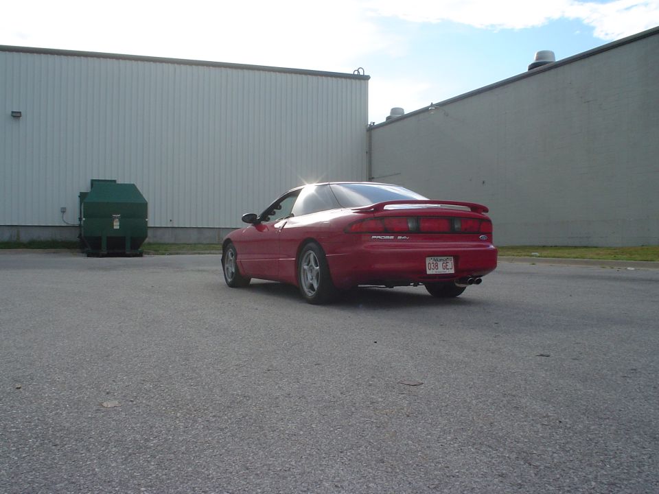 Red 1996 Ford Probe parked near a dumpster and industrial buildings