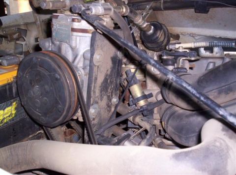1995 Ford Bronco - Close-up view of an AC compressor and associated hoses within an engine bay.
