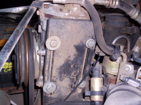 1995 Ford Bronco - Close-up view of engine components, including a dusty black housing and pulley system.