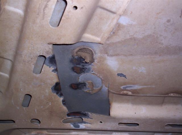 Underbody rust repair with visible patch and holes