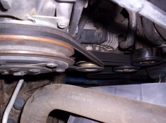 Close-up of engine belts and pulleys, with part number A-B3274-YC visible on a hose