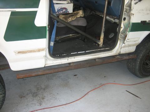 1994 Ford Bronco - The interior of a white Ford Bronco shows a roll cage and a green stripe on the exterior door panel.
