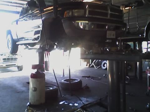 1992 Ford Bronco - Two trucks are visible on a lift inside a garage, with one in the foreground undergoing service.