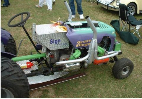 1968 Ford Mustang - A custom-built riding mower with a V8 engine and dual exhaust pipes is displayed on a grassy field.