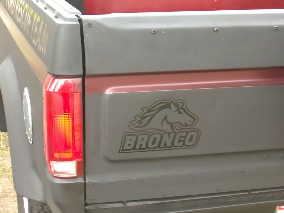 Rear corner of gray Ford Bronco with horse-head BRONCO decal on tailgate and red taillight