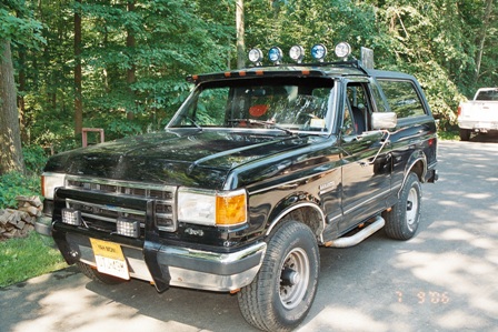 1991 Ford Bronco - Black 1991 Ford Bronco parked outdoors with trees in the background.