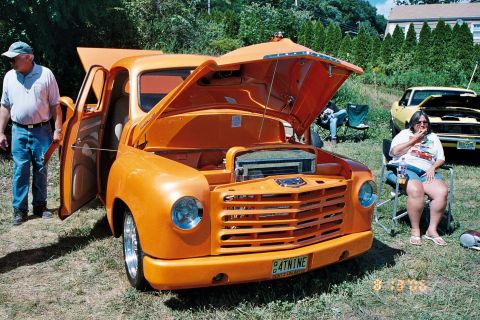 1991 Ford Bronco - An orange pickup truck is displayed with its hood and doors open at an outdoor car show.