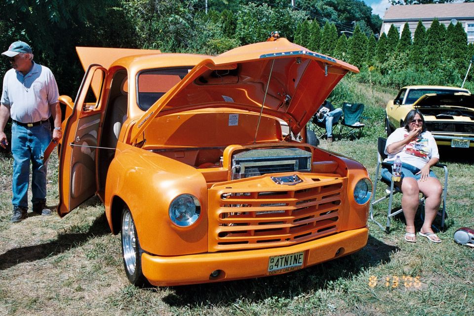 Orange pickup truck with hood and doors open, custom grille, license plate 4TNINE