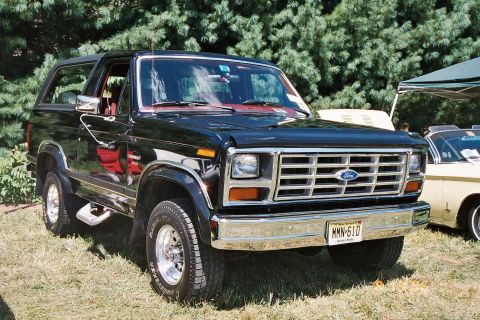 1991 Ford Bronco - This black Ford Bronco, likely from the early 1980s, is shown at a car show with another vehicle partially visible to the right.
