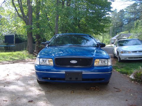 1998 Ford Crown Victoria - A blue Ford Crown Victoria is parked in front of a house, with another car visible to the right.