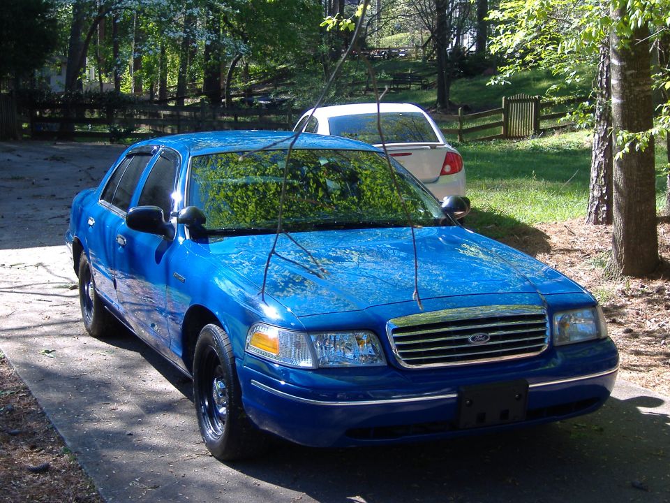 Blue sedan with black wheels and chrome grille, parked on a driveway