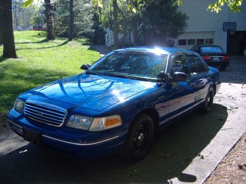 1998 Ford Crown Victoria - Blue 1998 Ford Crown Victoria sits in a driveway with a garage and trees behind it.