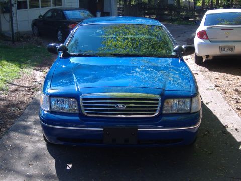 1998 Ford Crown Victoria - Front view of a blue Ford Crown Victoria parked in a driveway with two other vehicles visible.