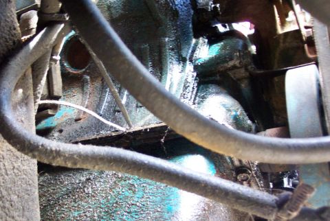 1975 Ford F-150 - This image shows a close-up view of engine parts, including hoses and a greasy block.