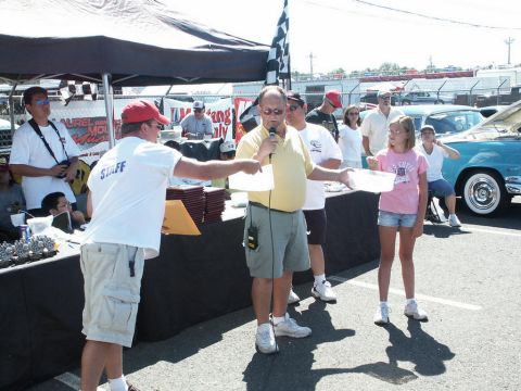 2001 Mercury Grand Marquis - A car show event with staff members and attendees gathered around a table, with a classic car visible.