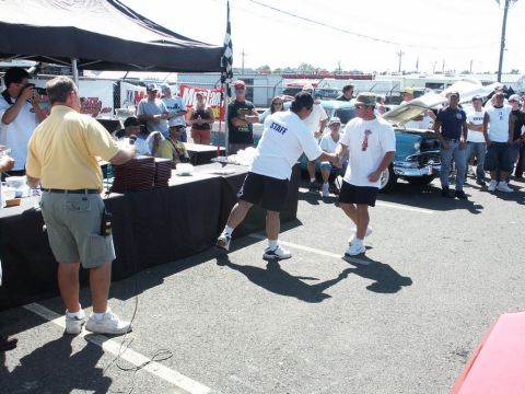 2001 Mercury Grand Marquis - People gather at an outdoor car show event, with a checkered flag visible and a blue car on display.