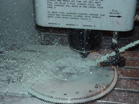 1979 Ford Bronco - A gear is being machined with coolant spraying, and warning labels are visible on the equipment.